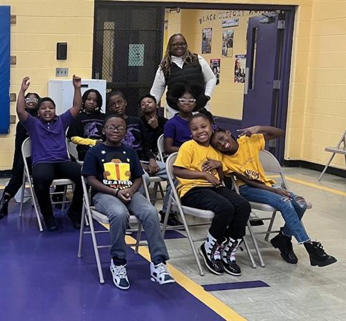  nine sitting students smiling and one standing smiling teacher